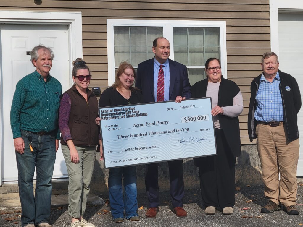 A closer view of the $300,000 check held by a tall man in a suit. Six other people are lined up in the picture.
