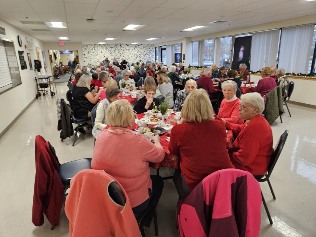 The Council on Aging cafeteria is packed with round tables full of older people chatting and eating.
