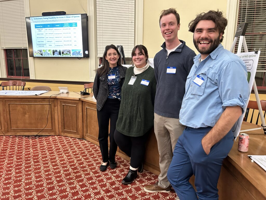 Four smiling people lined up waiting for open house to start.