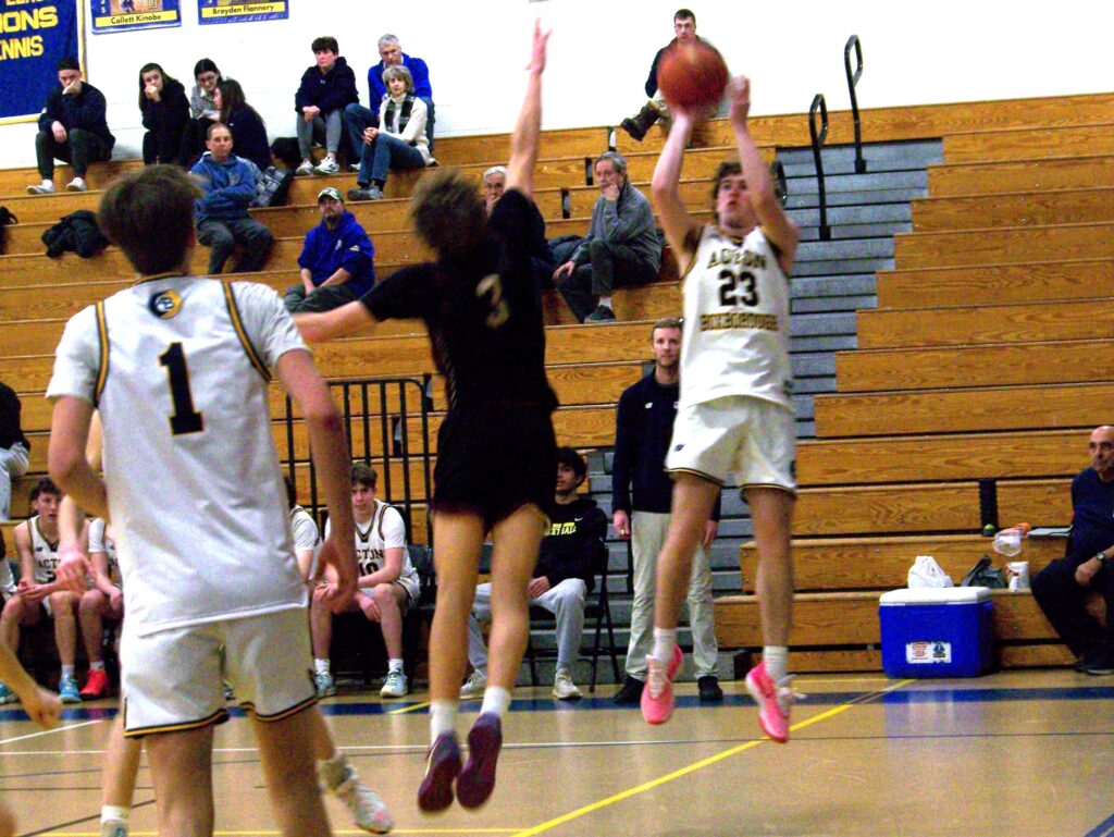 An AB player (with pink sneakers) catches some air while aiming a shot over the head of a CC player.