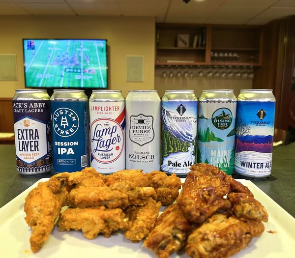 A lineup of local brews with a plate of wings in the front.