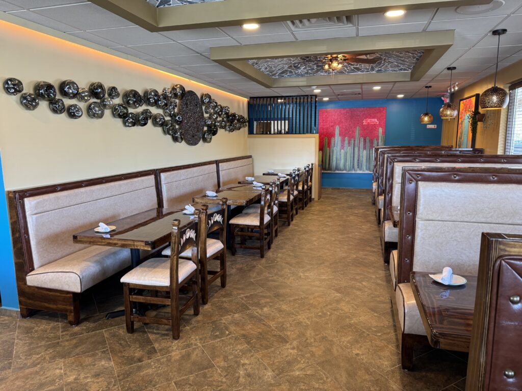 A long dining room with both booths and table seating and interesting looking art on the wall.