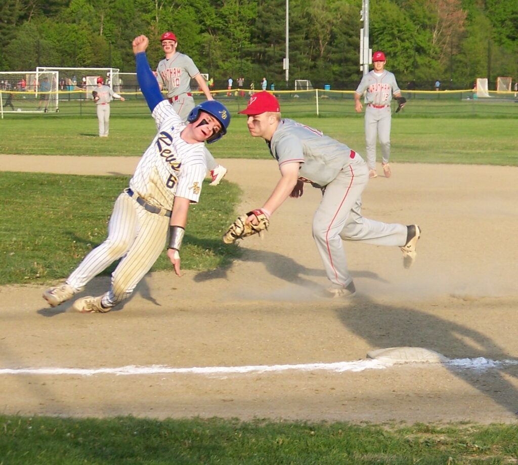 In a balletic move, a Rev's plaer begins a slide into a base while trying to avoid another player who is trying to tag him.