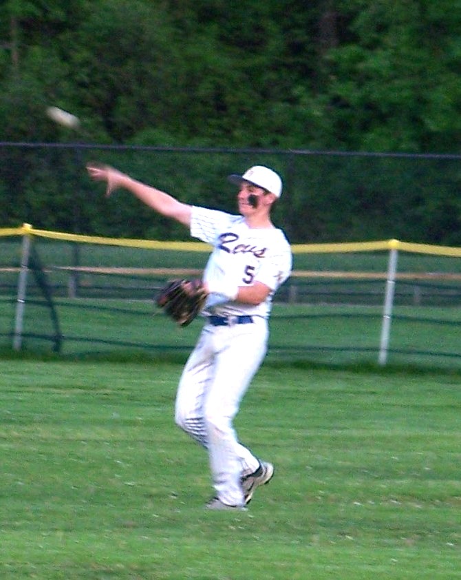 A baseball player in a Revs uniform throws a ball.