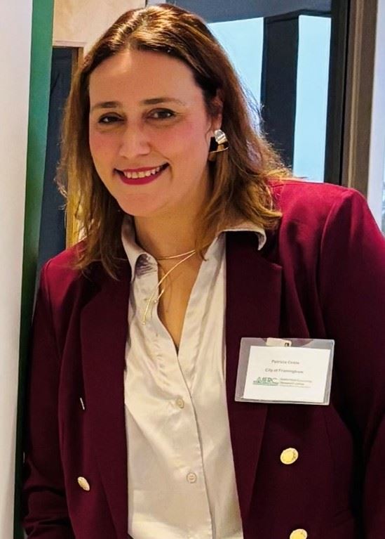 A smiling woman wearing a maroon jacket and matching lipstick.