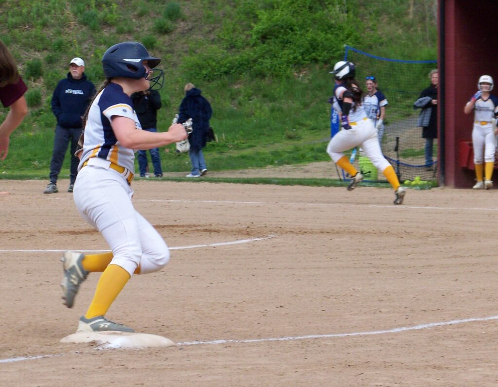 In the background, a Revs player is running to the next base. In the foreground, another player makes it to a base.