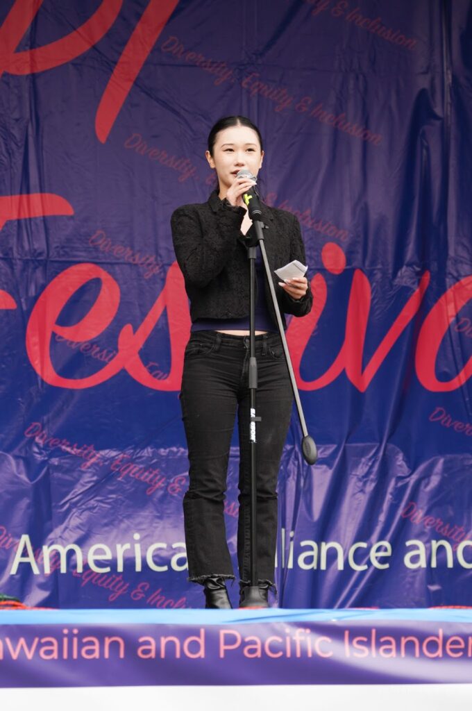 A young woman wearking black speaks into a microphone.