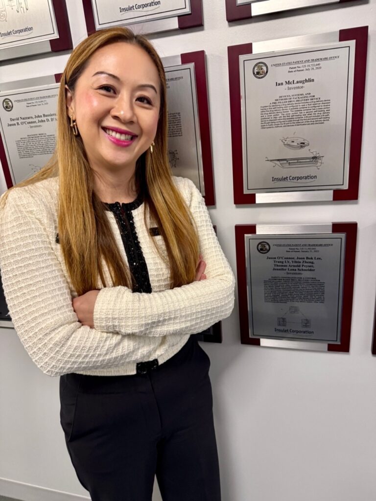 A woman stands in front of a wall full of patents issued to Insulet Corporation employees.