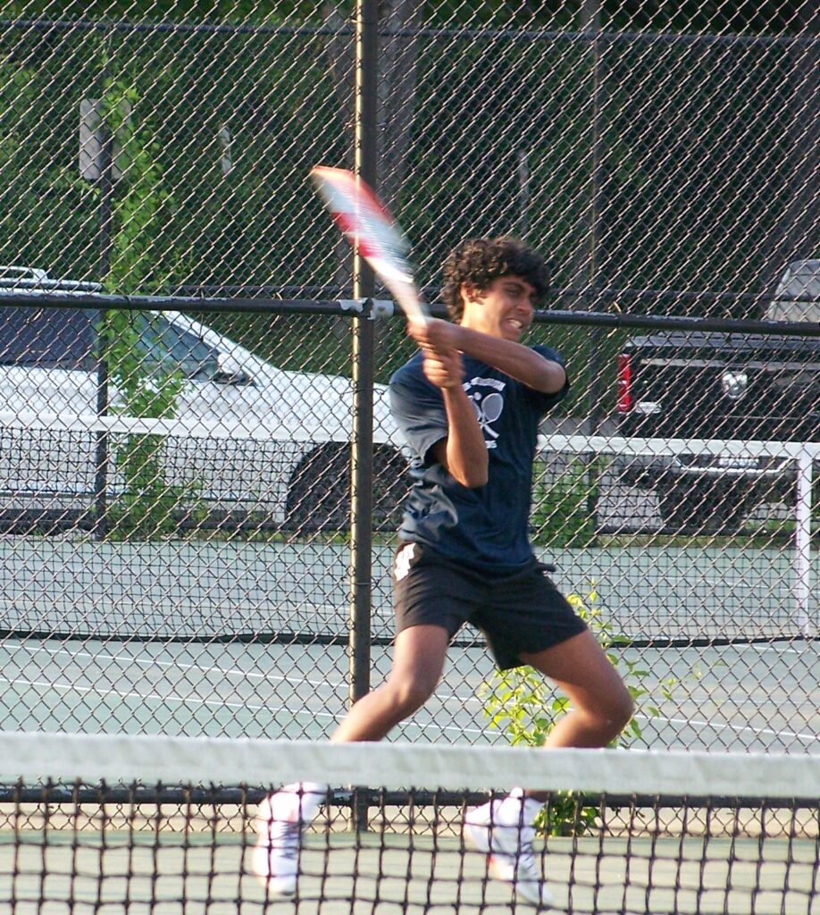 An AB tennis player has both hands on a moving racquet.