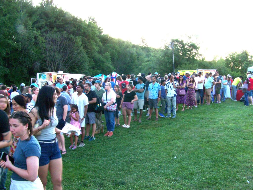 A very long line of people waits at the food (and in this case drink) trucks.