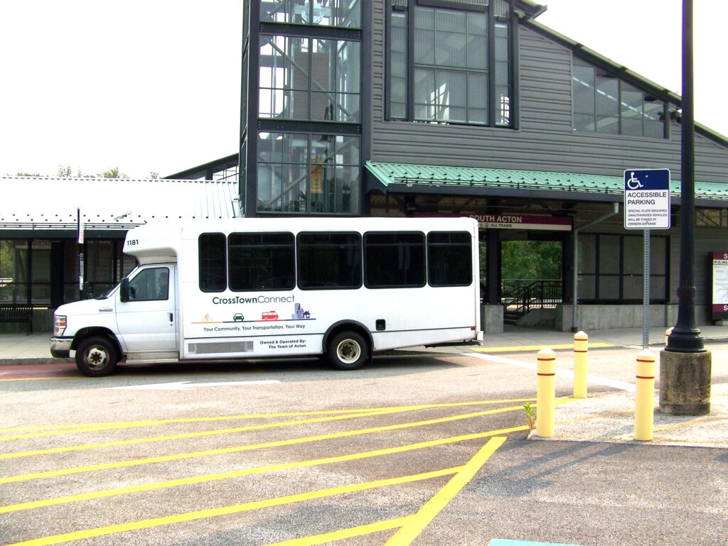 A white bus sits in front of the train station.