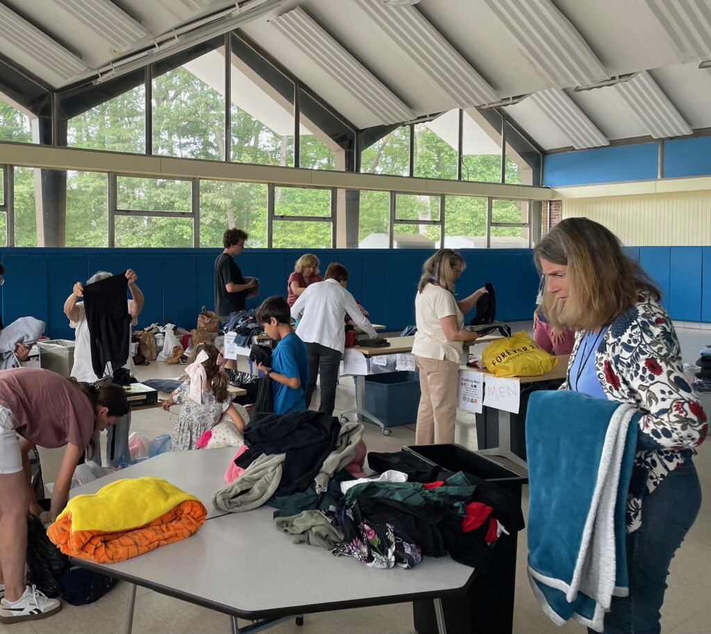 A large, well-lit room with tables full of clothing that people are organizing.