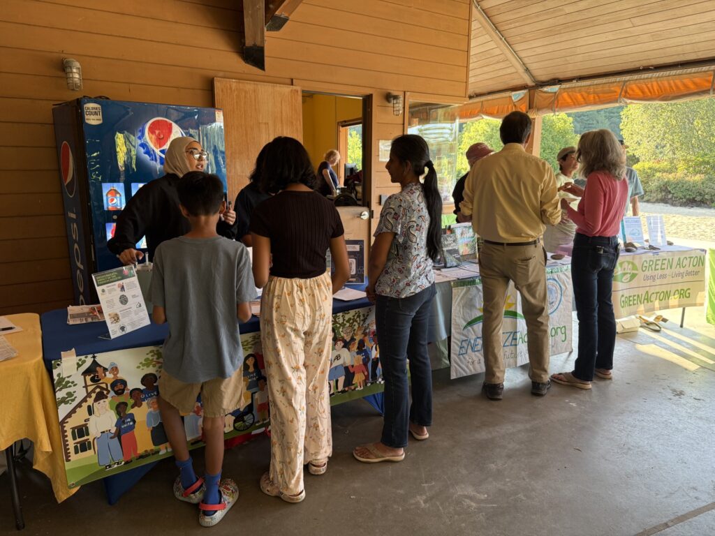 Several tables are lined up against a wall. Eco-night visitors chat with the people behind the tables.