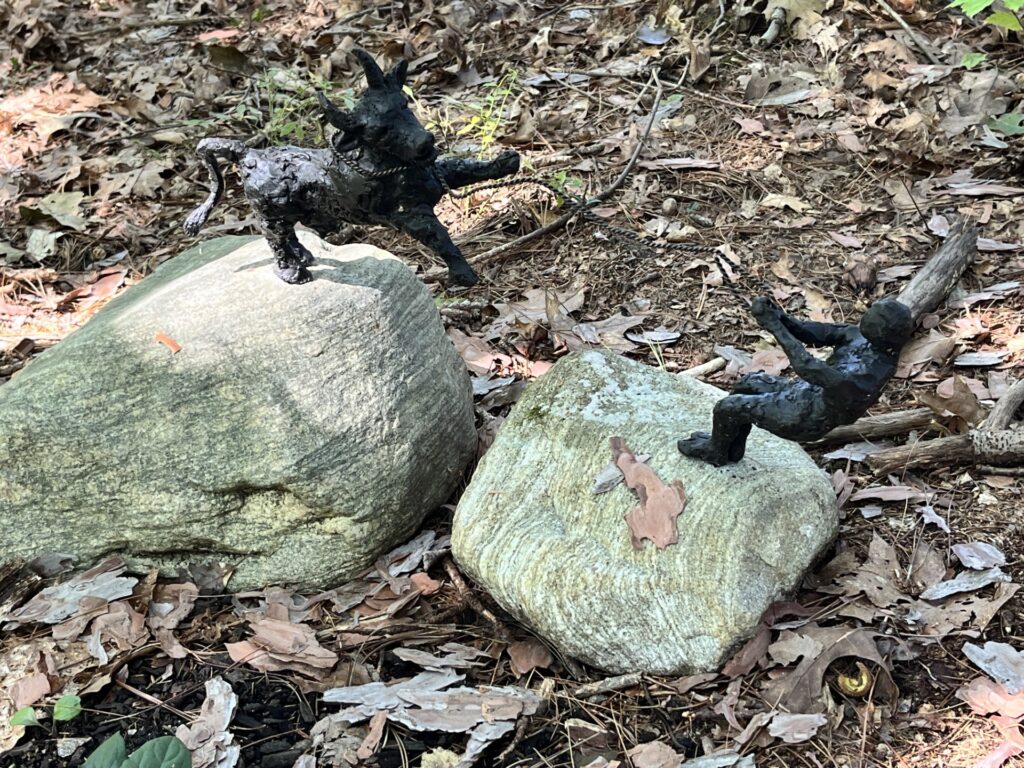 Two small figures on separate stones. One is an ox pulling back against a rope. the other is a person pulling on the rope to catch the ox.