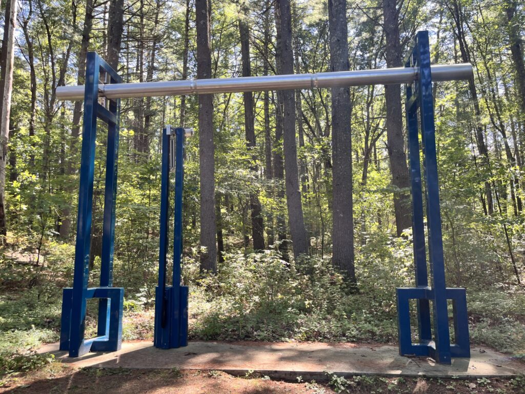 A large (maybe 10 feet tall) blue and silver sculpture made from blue square tubes and a silver cylindar. The sculpture includes a large bell pull that, when pulled, brings a hammer up against the cylindar, which can vibrate for many minutes.