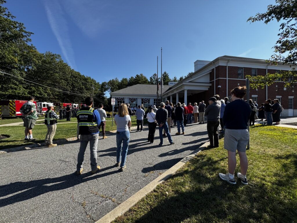 People stand in front of the Public Safety Building listening to speeches.