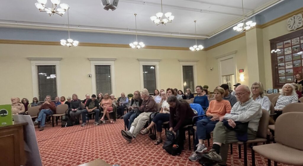 The chairs are full in Acton Town Hall room 204.