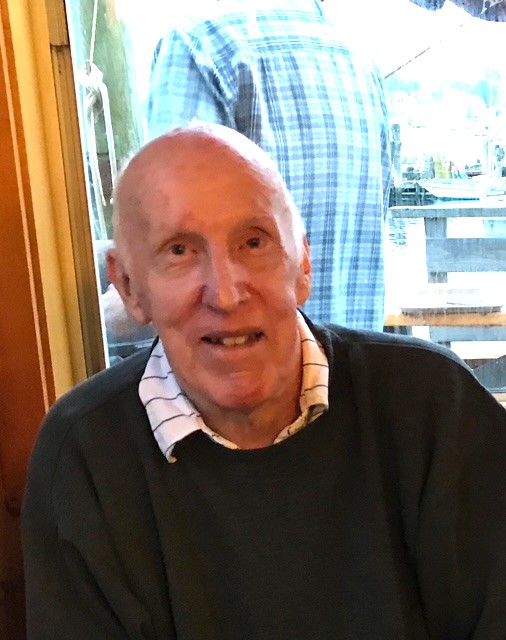 An older man wearing a button-down shirt and a sweater.