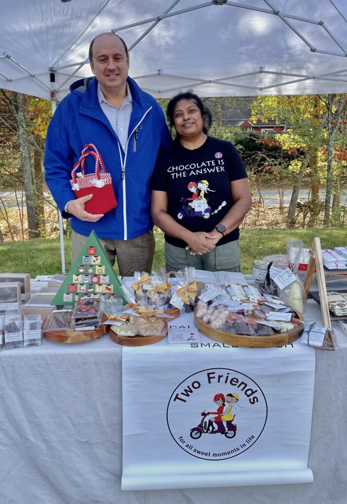 A tall man in a blue jacket stands next to a much shorter woman wearing a "Chocolate is the answer" t-shirt.