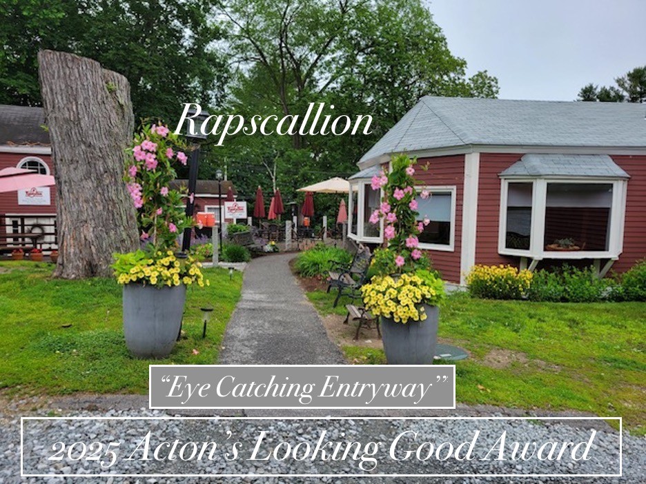 A path to the restaurant with large buckets full of yellow and pink flowers.
