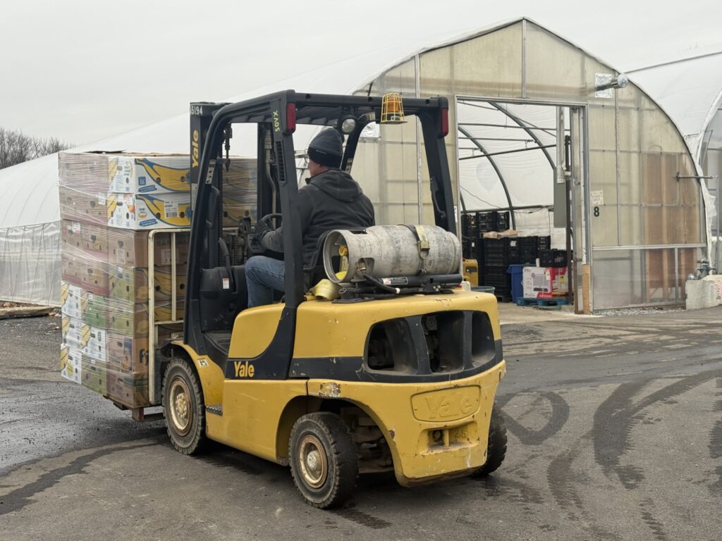 A person drives a forklift stacked with boxes of food.