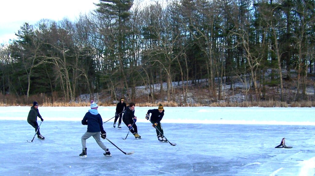 A group of kids playing pickup hockey on an outdoor pond.