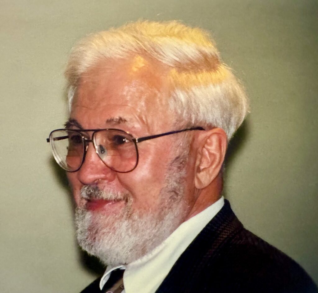 A smiling man with white hiar and beard.