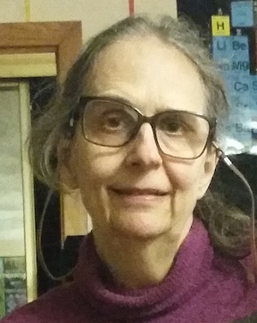 A woman with big glasses wearing a purple sweater.