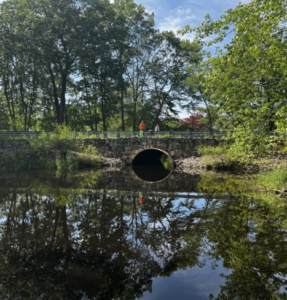 Two people stand on an old bridge. The culvert is the archway through the bridge.
