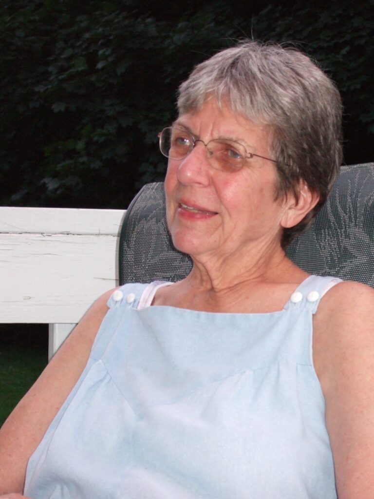 A laughing woman in a sleevelss shirt sits in a chair.