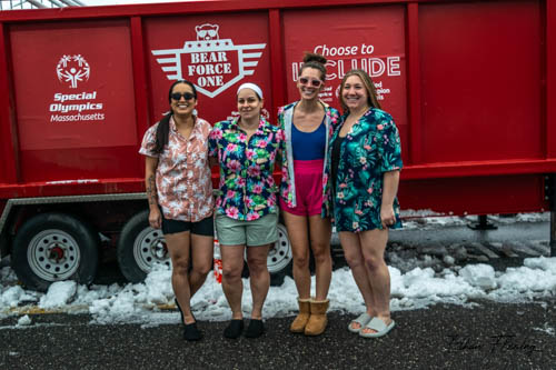 Four women stand in front of the plunge tank wearing brigh Hawaiian shirts and shorts.