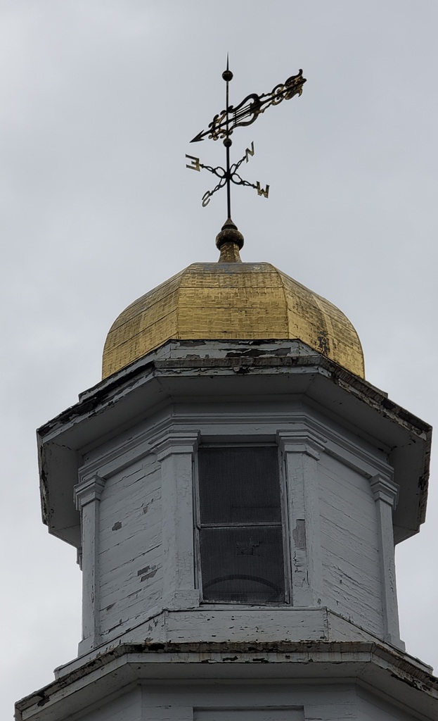 The belfry and dome up close. The paint is chipped and there's some rotten wood. The gold leaf is also looking worn.